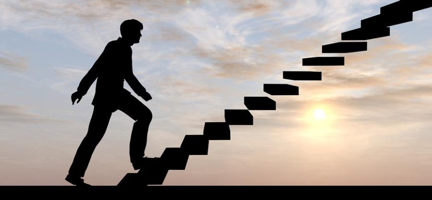 The Psychology of Resolutions. Picture of man climbing up into the sky one step at a time. This is to show the Psychology of Resolutions by taking one step at a time.